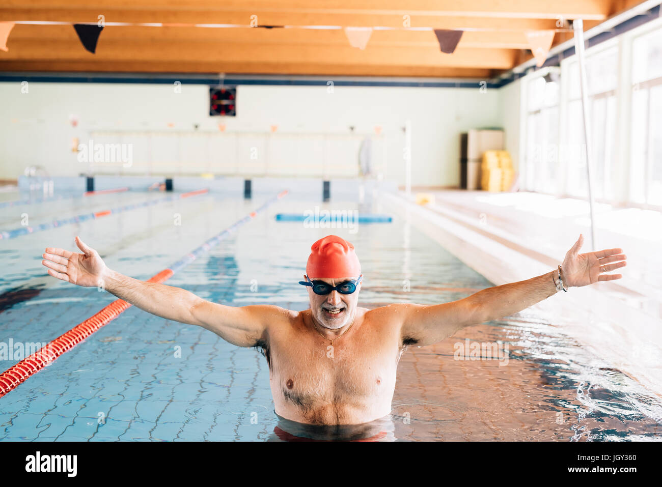 Senior uomo con le braccia aperte in piscina Foto Stock