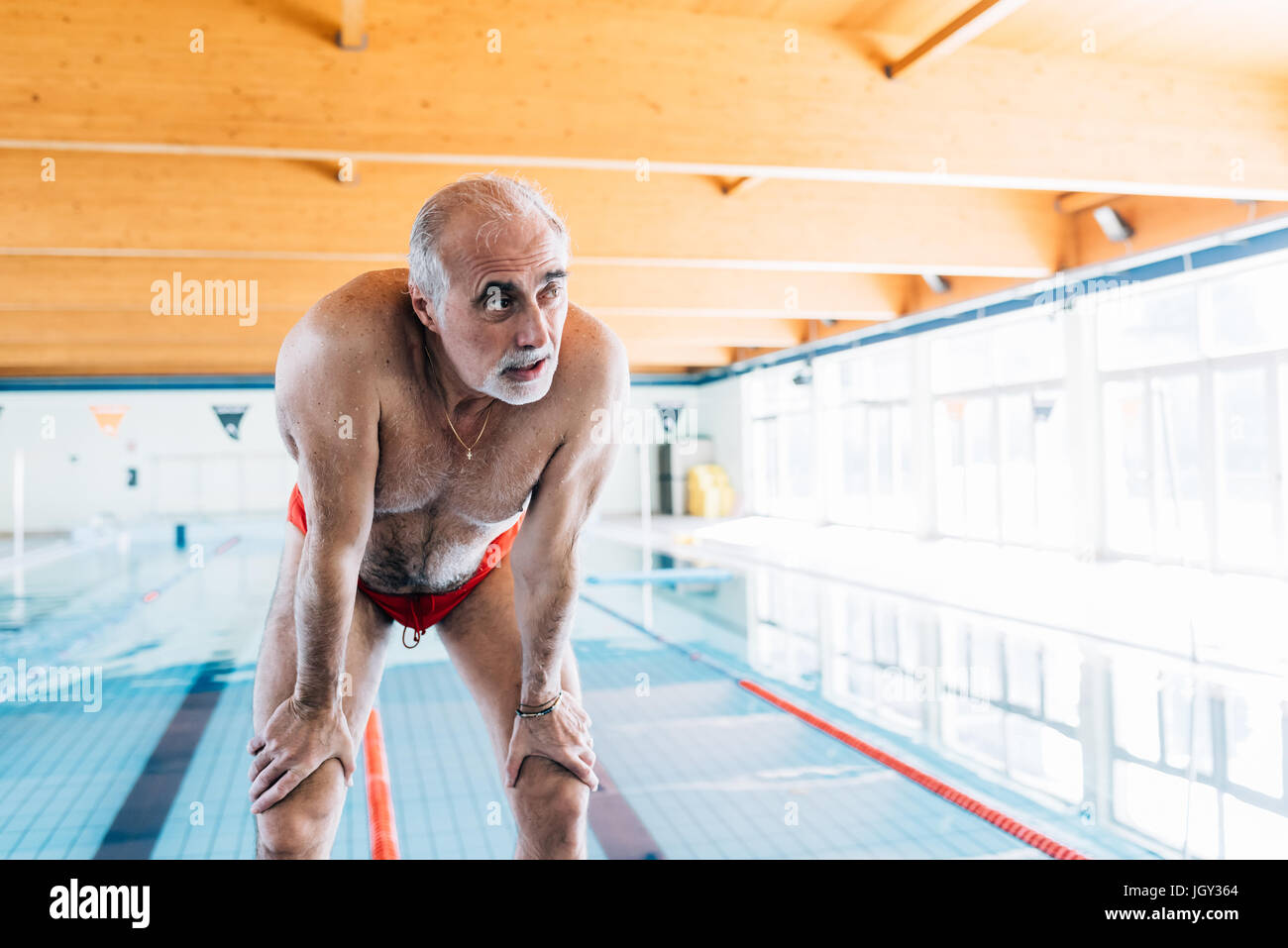 Senior uomo piegamenti cattura il suo respirare da piscina Foto Stock