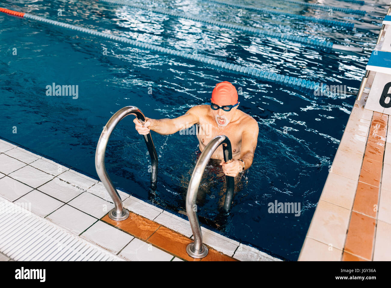Senior uomo con scaletta in piscina Foto Stock