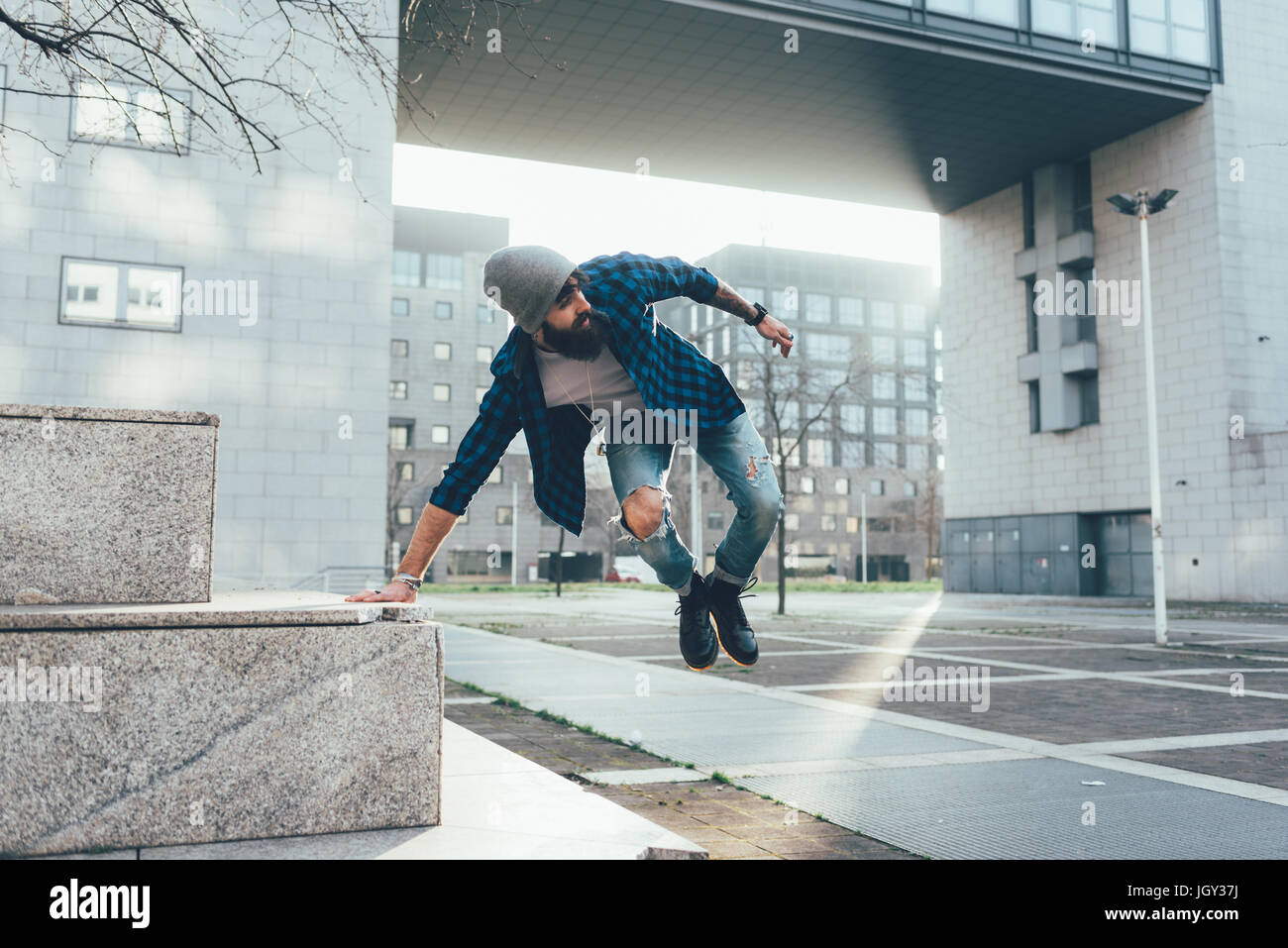 Giovane maschio hipster jumping metà aria pratica parkour in città Foto Stock