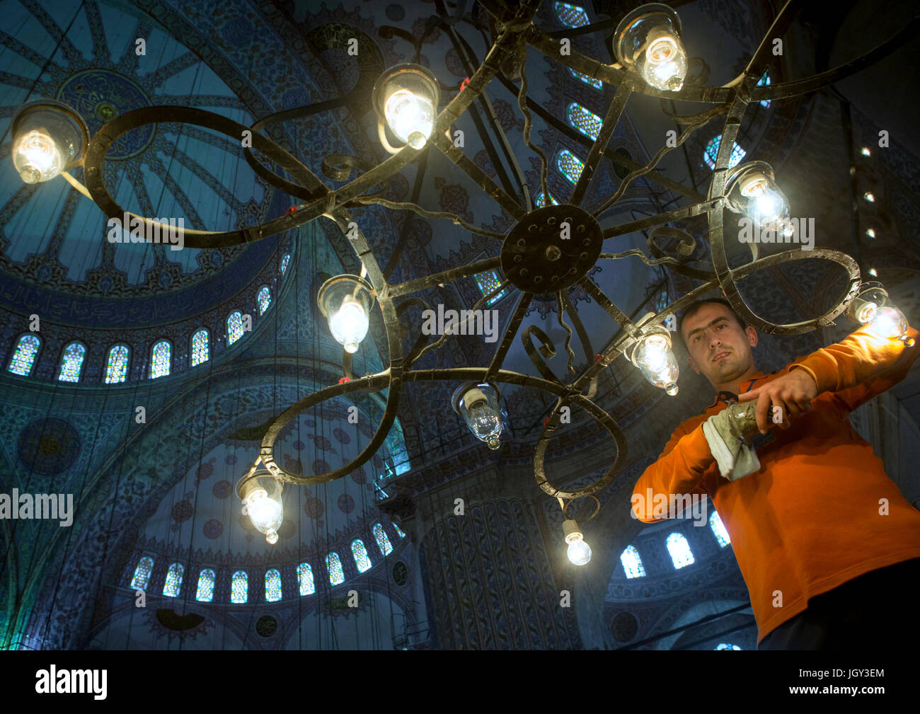 L'uomo modifica le lampade all'interno della Moschea Blu Sultan Ahmet Camii, Sultanahmet, Istanbul, Turchia Foto Stock