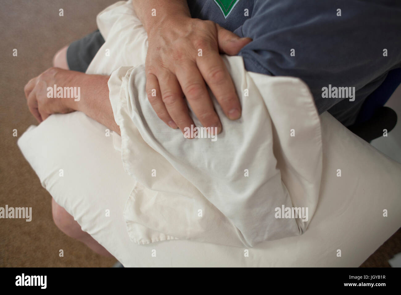 Un uomo si siede con una confezione di ghiaccio durante la terapia fisica. Foto Stock
