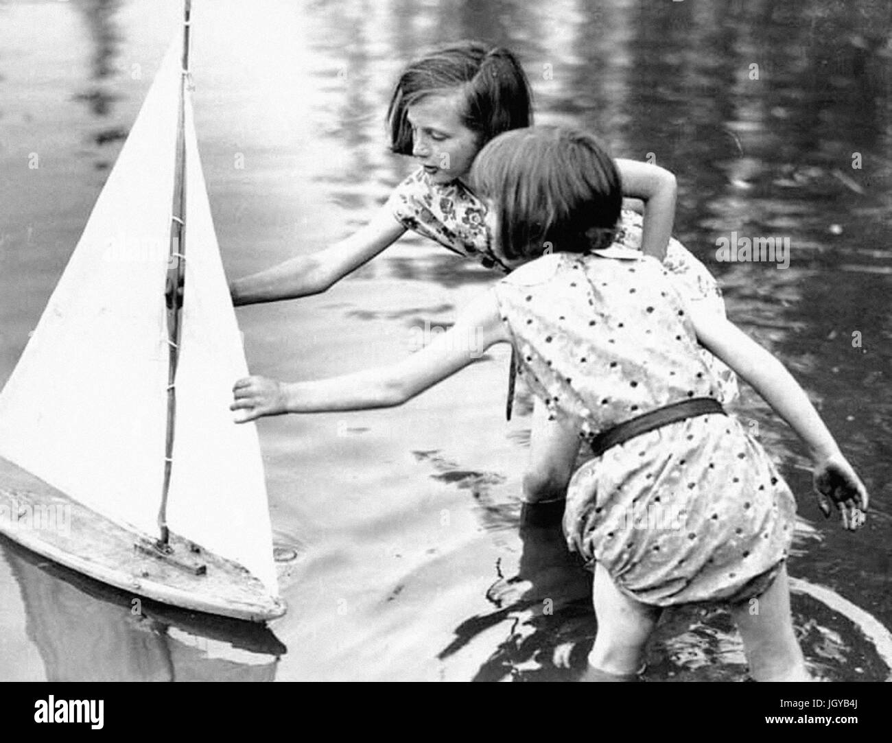 Passatempi vecchio - due ragazze di raggiungere per un giocattolo di barca a vela, Seattle, Washington Foto Stock