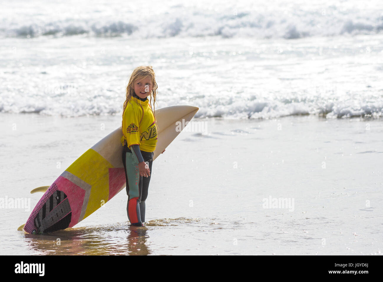 Navigare in UK. Un ottavo anno vecchio surfer in attesa di competere nel Regno Unito scuole surf campionato. Nerf scontro di Groms a Fistral in Newquay, Cornwall. Foto Stock
