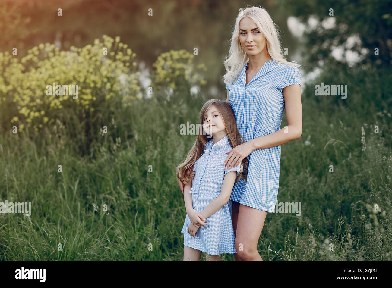 Mamma e figlia in belle abiti a piedi nel campo della bella estate meteo Foto Stock