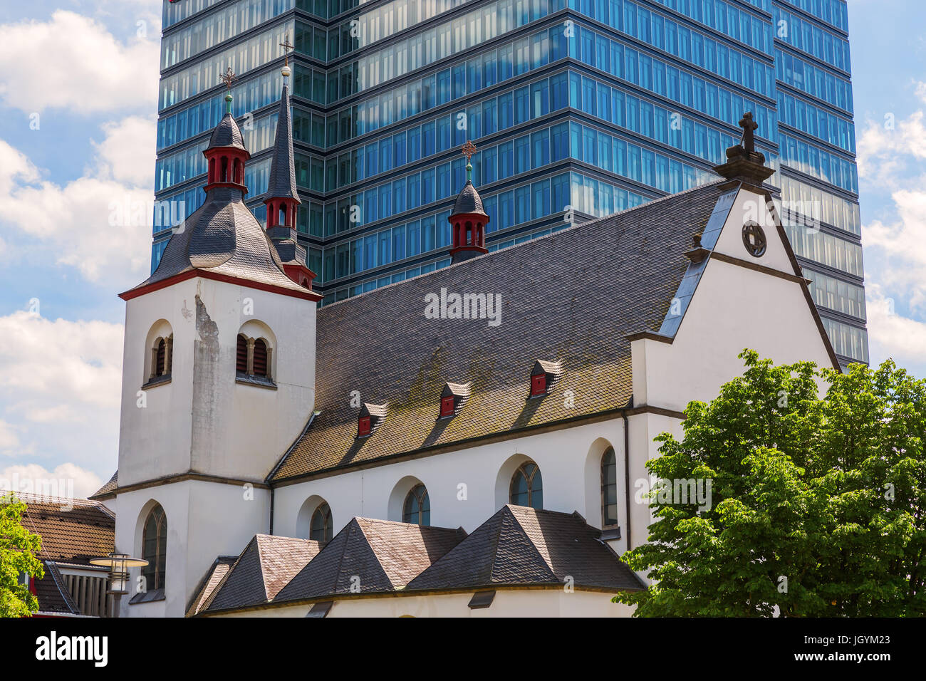 Chiesa di Alt St. Heribert davanti a una torre di uffici a Colonia, Germania Foto Stock