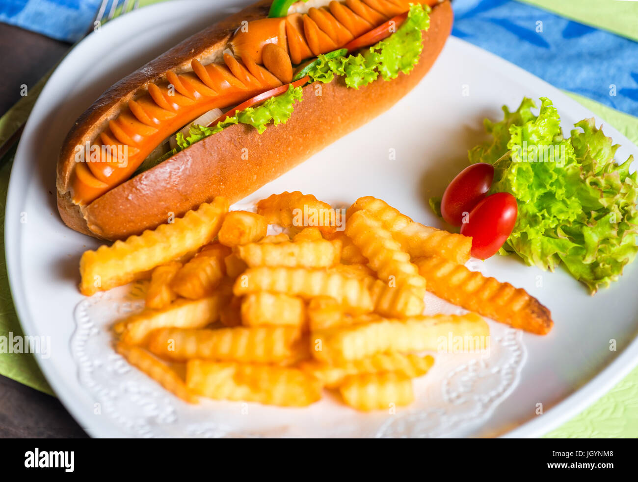 Panino con salsicce e patate fritte su una piastra Foto Stock
