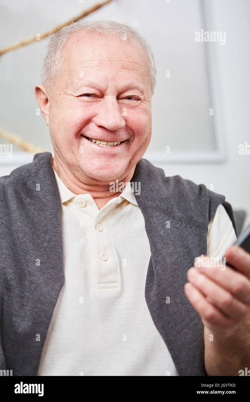 Felice l'uomo senior detiene smartphone e sorrisi con gioia Foto Stock