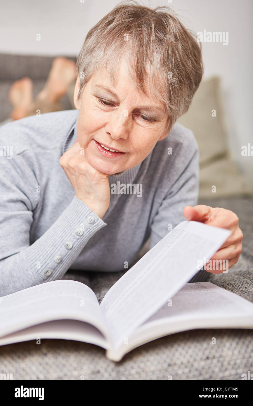 La donna come senior la lettura di un libro con curiosità Foto Stock