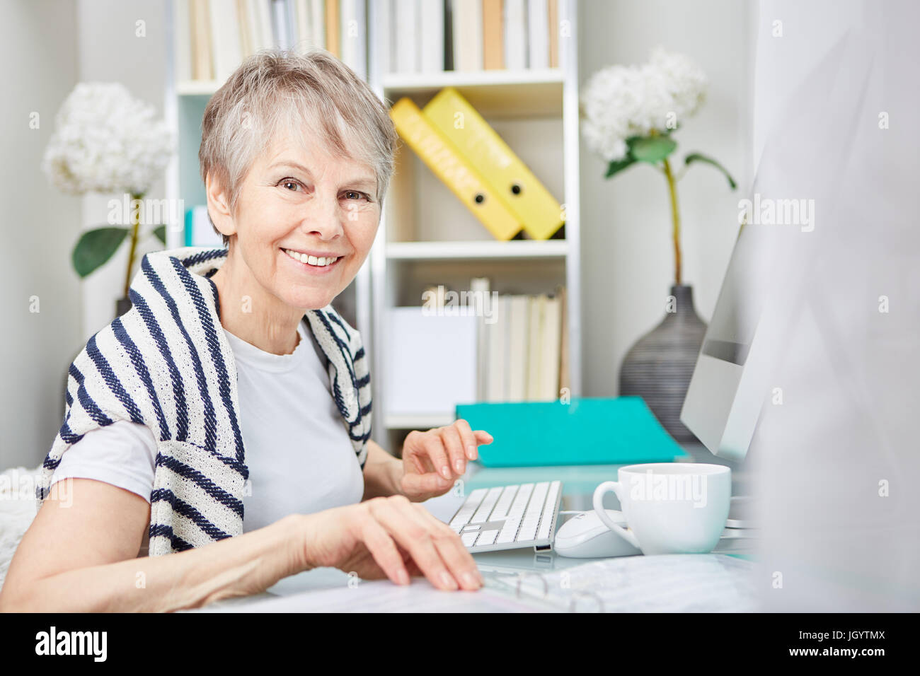 La donna come senior business cittadino lavora al suo posto di lavoro Foto Stock