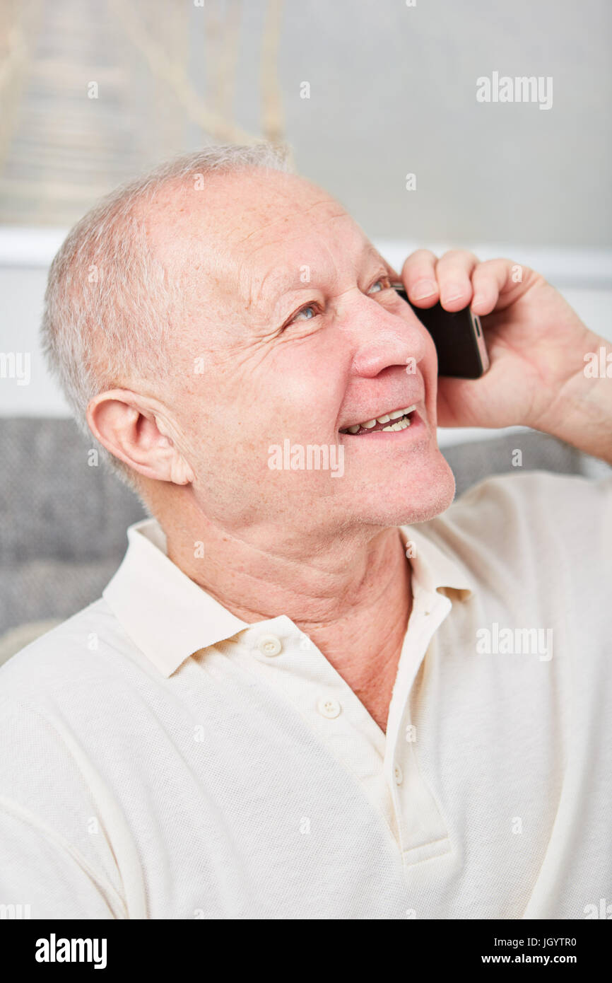 Senior uomo che ascolta con gioia il messaggio nello smartphone Foto Stock