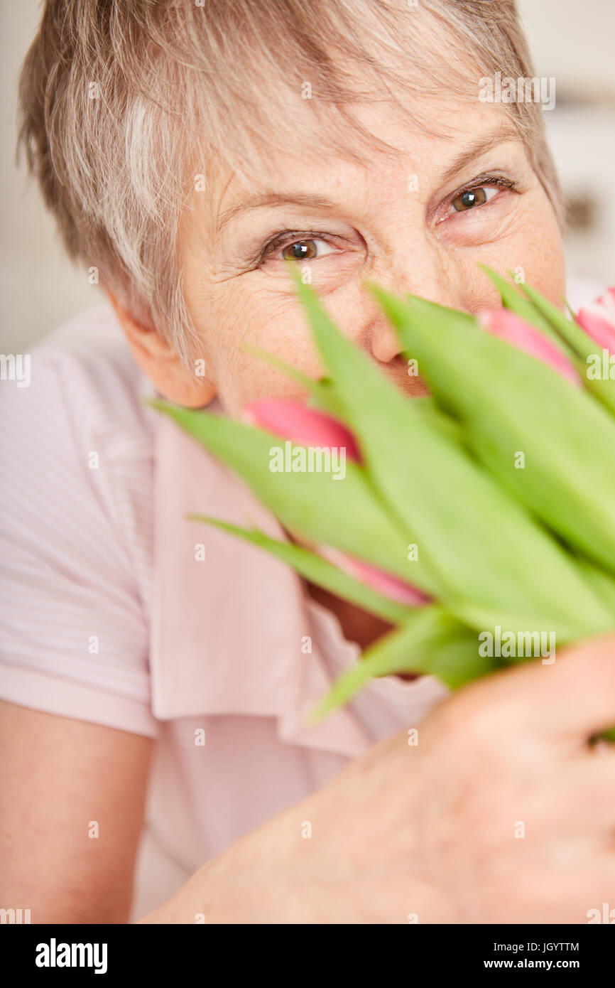 Senior donna odori bouquet per il suo compleanno Foto Stock