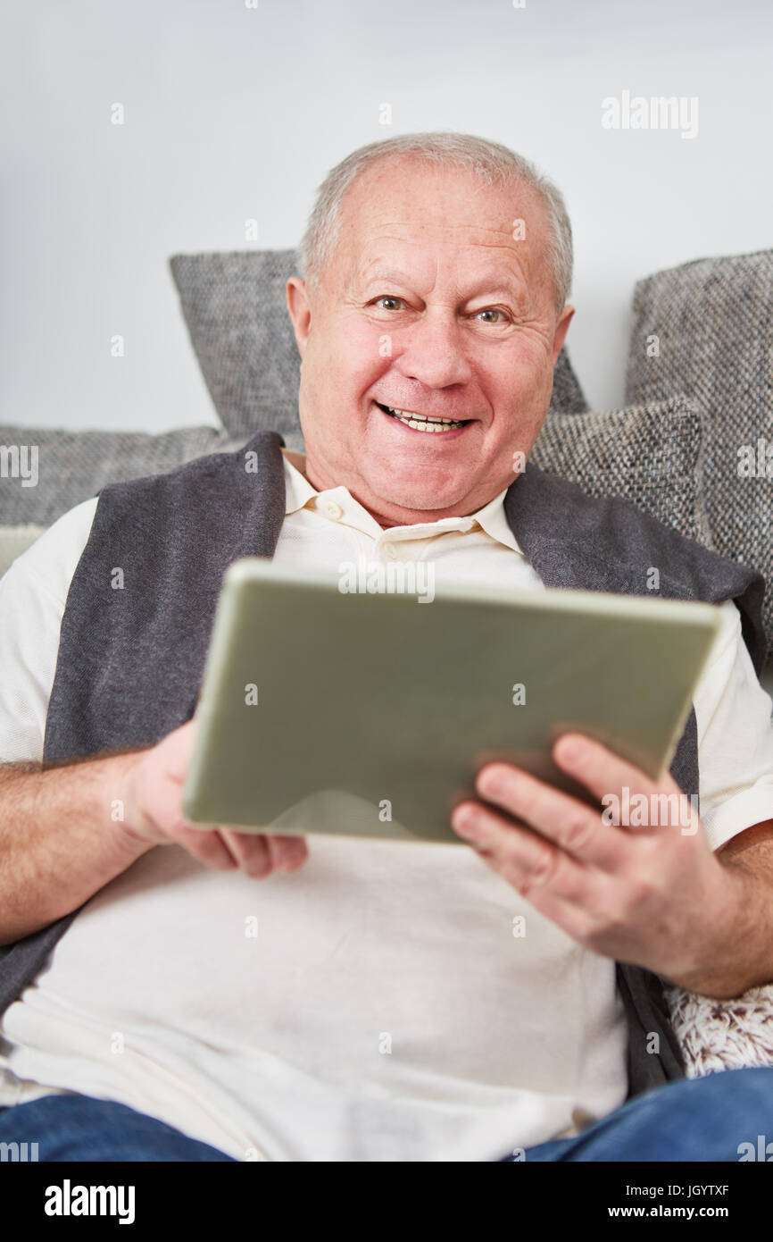 Senior moderno uomo detiene il tablet con gioia e impara circa la comunicazione on line Foto Stock
