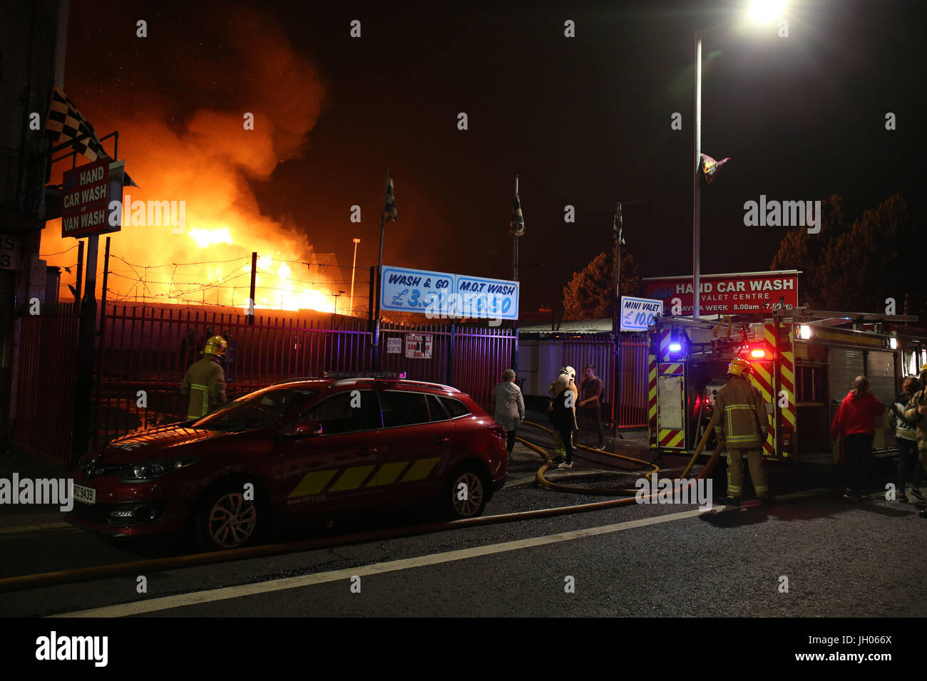 Vigili del fuoco smorzare vicino casa come un falò a Ravenscroft Avenue a Belfast è accesa prima della data chiave nella protestante ordine leale marching stagione - il dodicesimo di luglio. Foto Stock