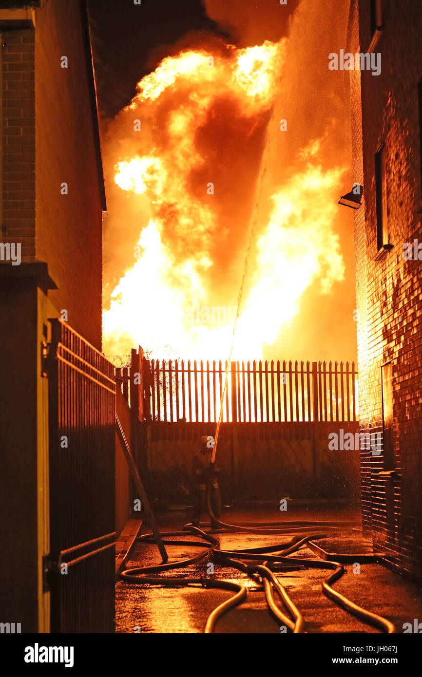 Vigili del fuoco smorzare vicino casa come un falò a Ravenscroft Avenue a Belfast è accesa prima della data chiave nella protestante ordine leale marching stagione - il dodicesimo di luglio. Foto Stock