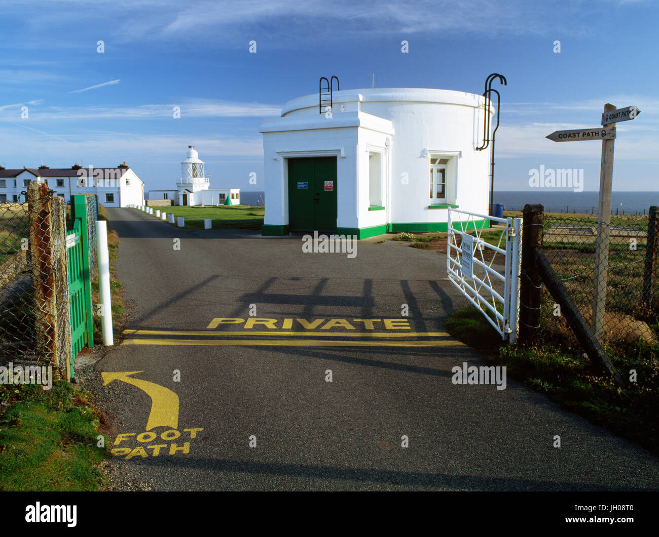 Gateway per St Ann's faro capo (sullo sfondo al centro) Il Pembrokeshire Coast a lunga distanza sentiero attraversa l'accesso privato road. Wales, Regno Unito Foto Stock