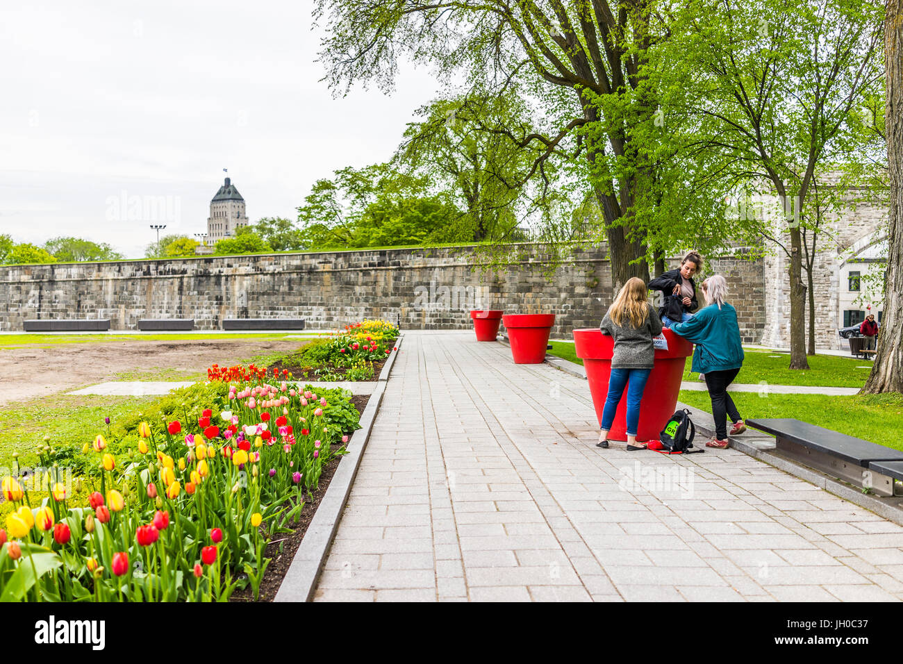 La città di Quebec, Canada - 29 Maggio 2017: erba verde pianura campi nel parco con fortificazioni muro di pietra e la gente seduta sui grandi vasi di fiori Foto Stock