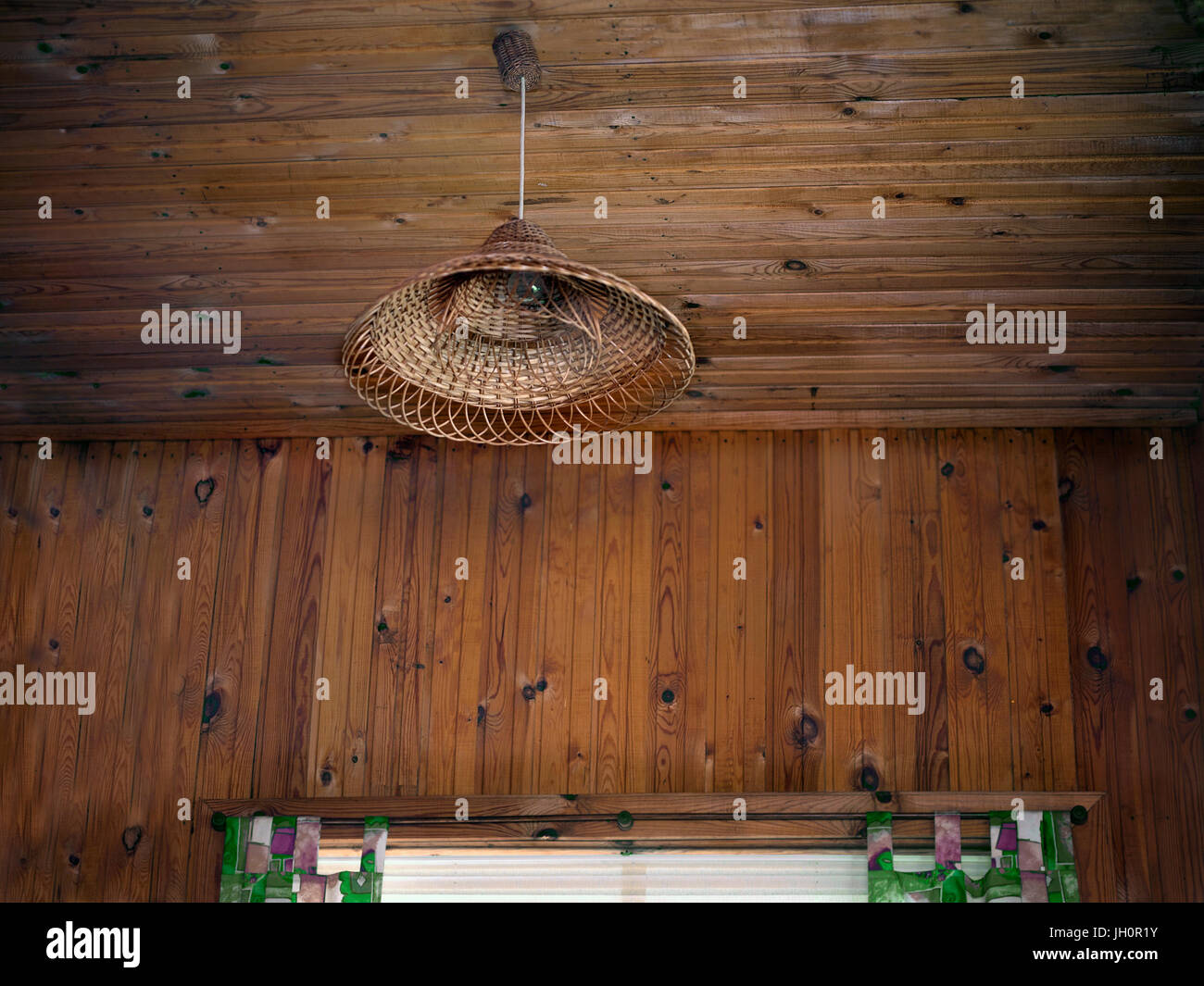Bassa angolazione di una camera in legno con una lampada di vimini sul soffitto. Foto di filtrato. Foto Stock