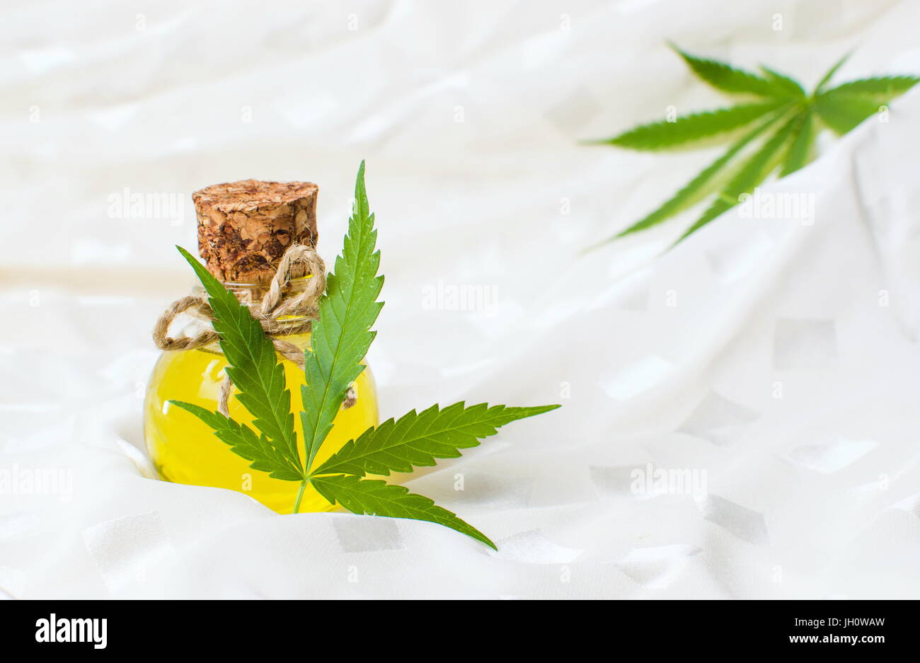 Olio di cannabis e marijuana foglia sul tessuto bianco Foto Stock