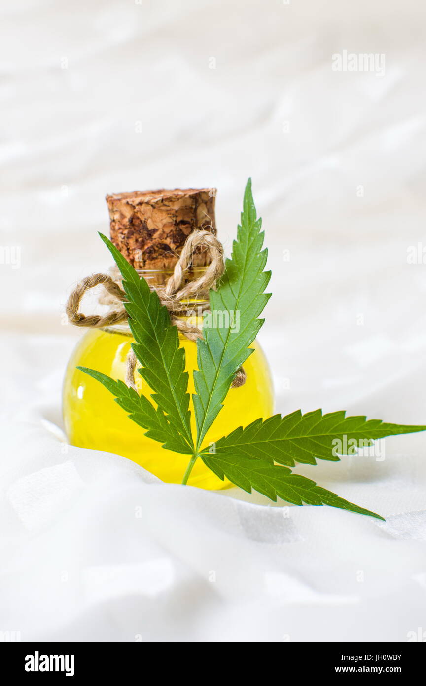 Olio di cannabis e marijuana foglia sul tessuto bianco Foto Stock