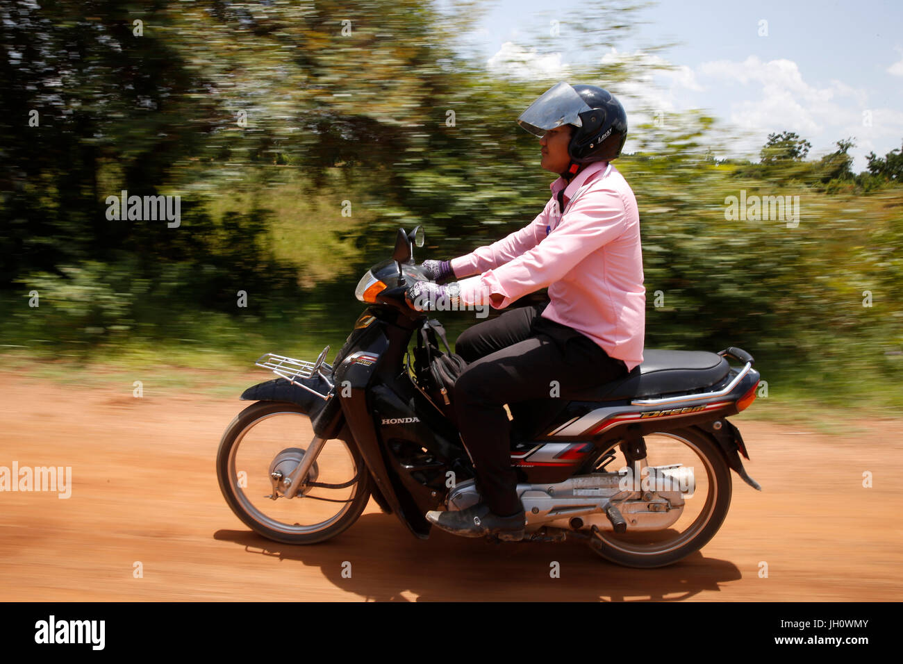 La microfinanza credit officer in sella a una motocicletta per visitare i clienti. Cambogia. Foto Stock