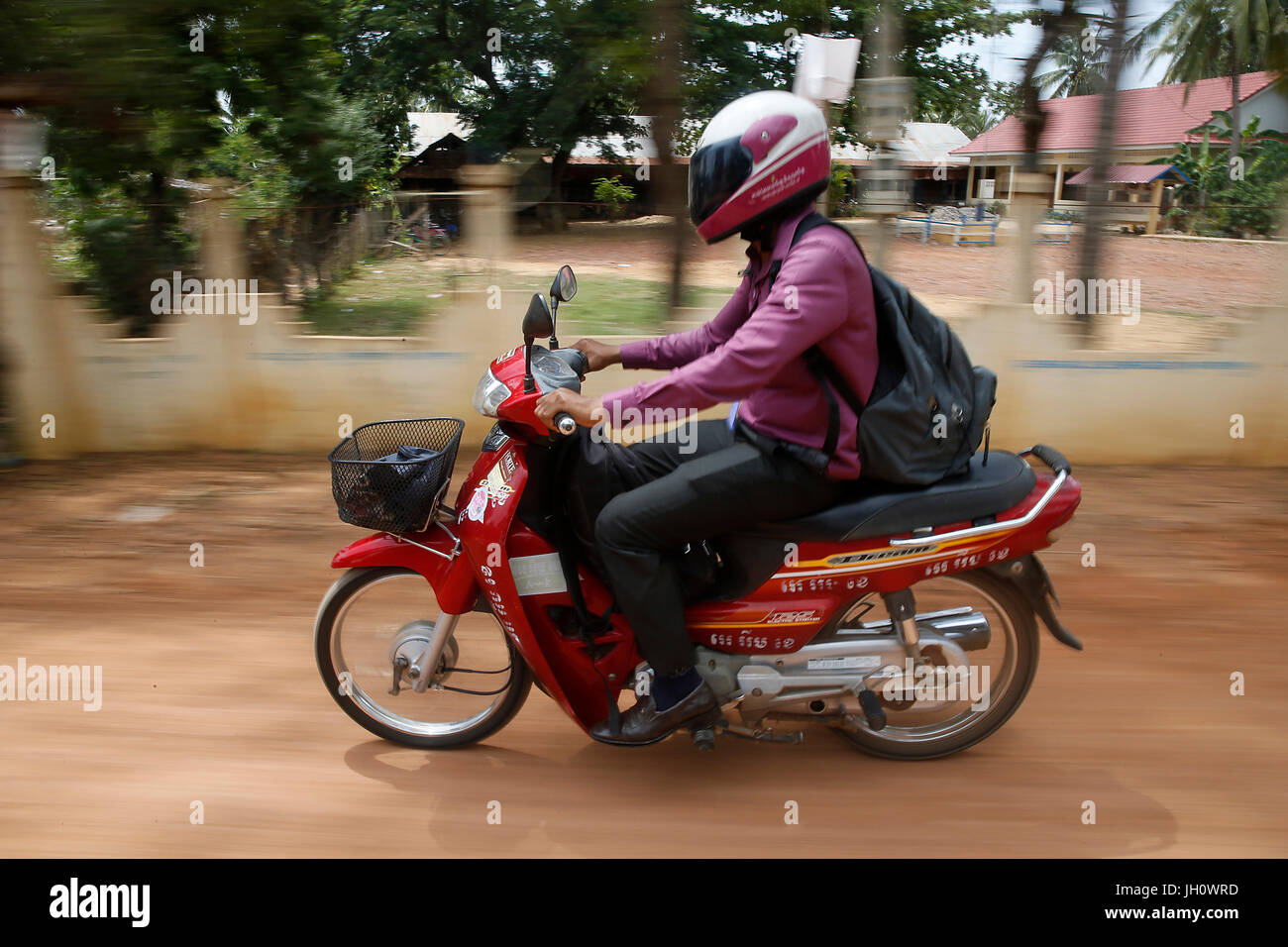 AMK dipendente di microfinanza in sella al suo scooter per visitare i clienti. Cambogia. Foto Stock