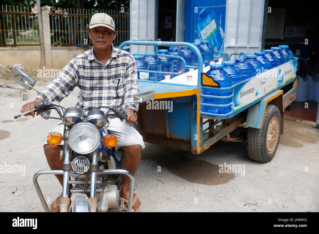 1001 Fontane acqua società dipendente alla guida di un carrello per la consegna. Cambogia. Foto Stock