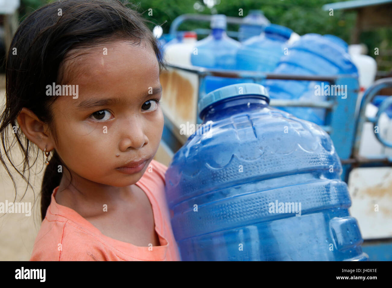 Ragazza cambogiano tenendo un demijohn d'acqua. Cambogia. Foto Stock