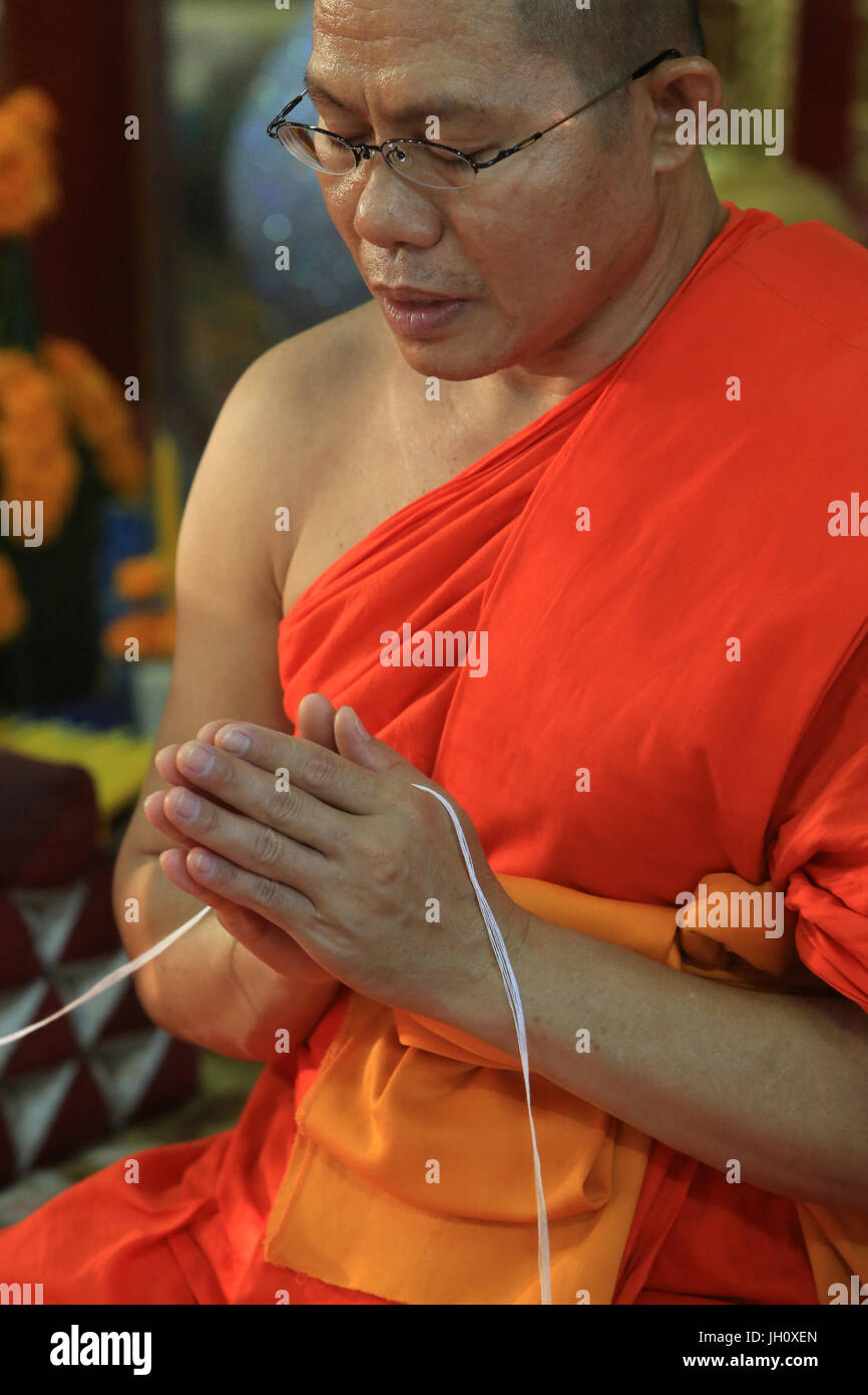 Sai il peccato. Filo di cotone che simboleggia il legame sacro. Monaco buddista di pregare. Cerimonia buddista. Wat Simuong. Wat Si Muang. Vientiane. Laos. Foto Stock