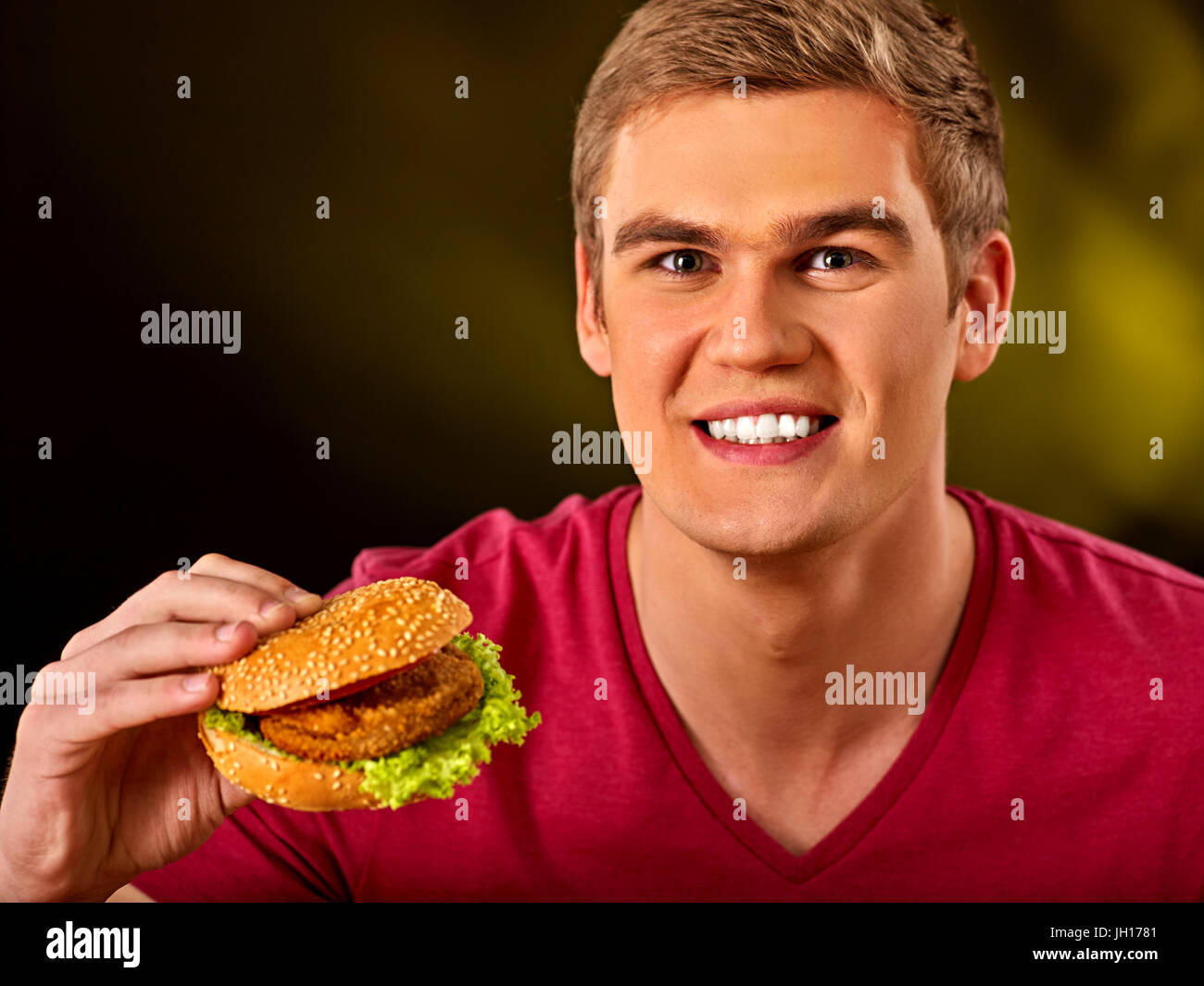 L'uomo mangiare hamburger. Ragazzo morso del grande burger Foto Stock