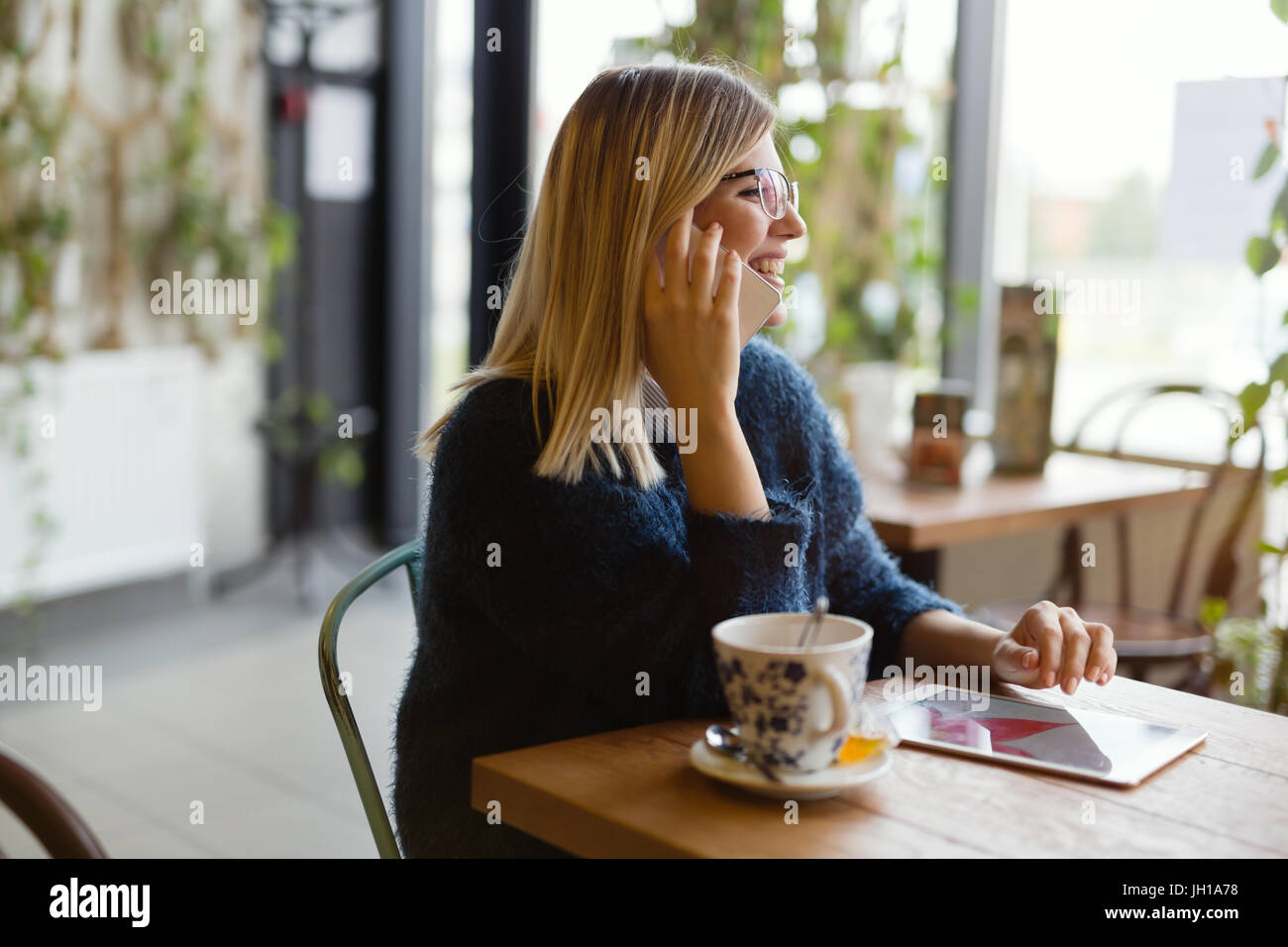 Bella giovane donna con tavoletta digitale presso la caffetteria Foto Stock