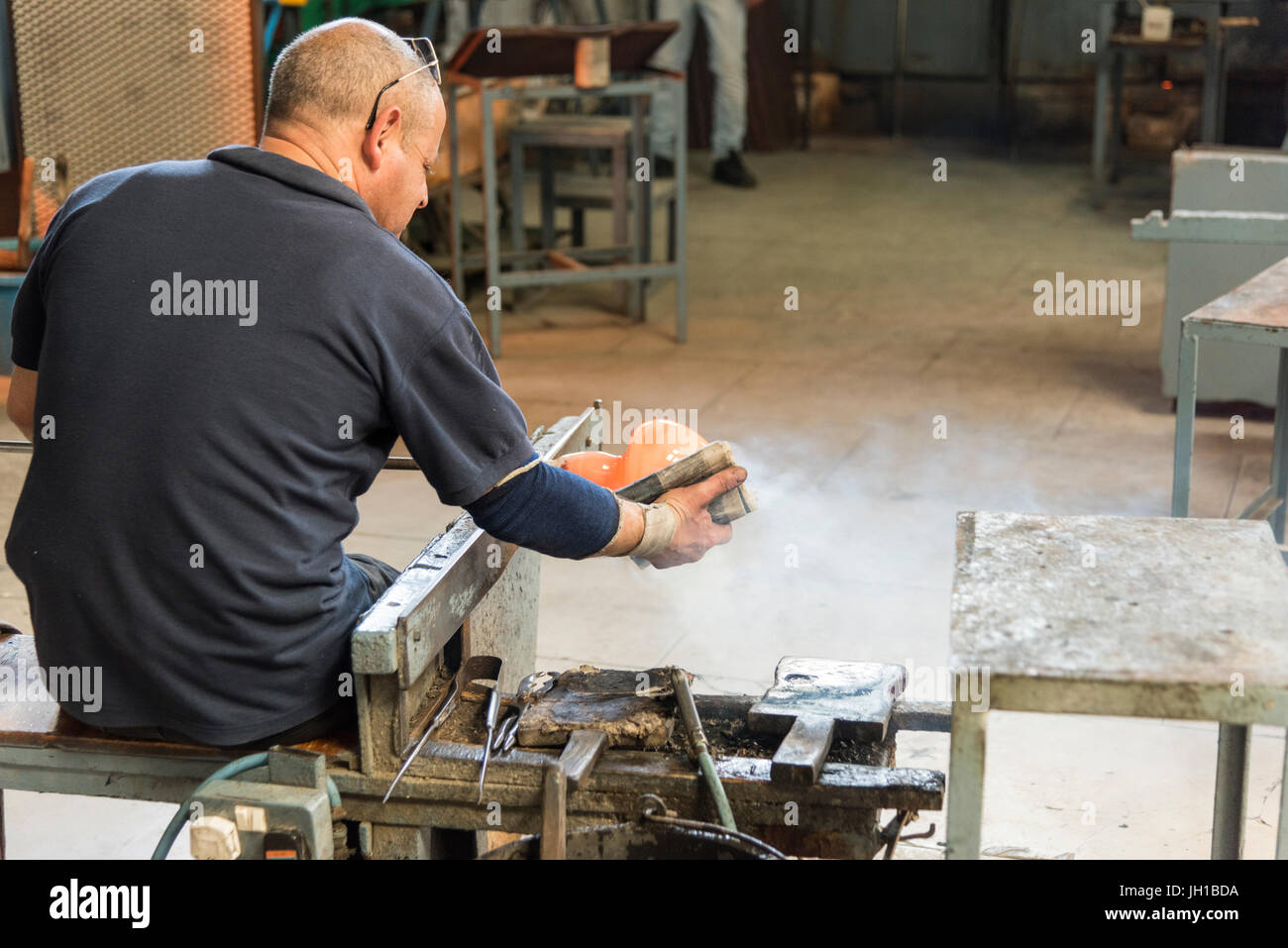 Un soffiatore di vetro al lavoro facendo una ciotola di vetro dal vetro fuso in Mdina Fabbrica del Vetro a Malta Foto Stock