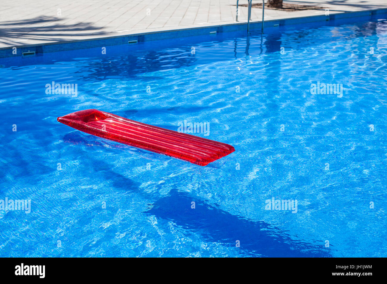 Rosso di lilo gonfiabile Lettino flottante in una piscina Foto Stock