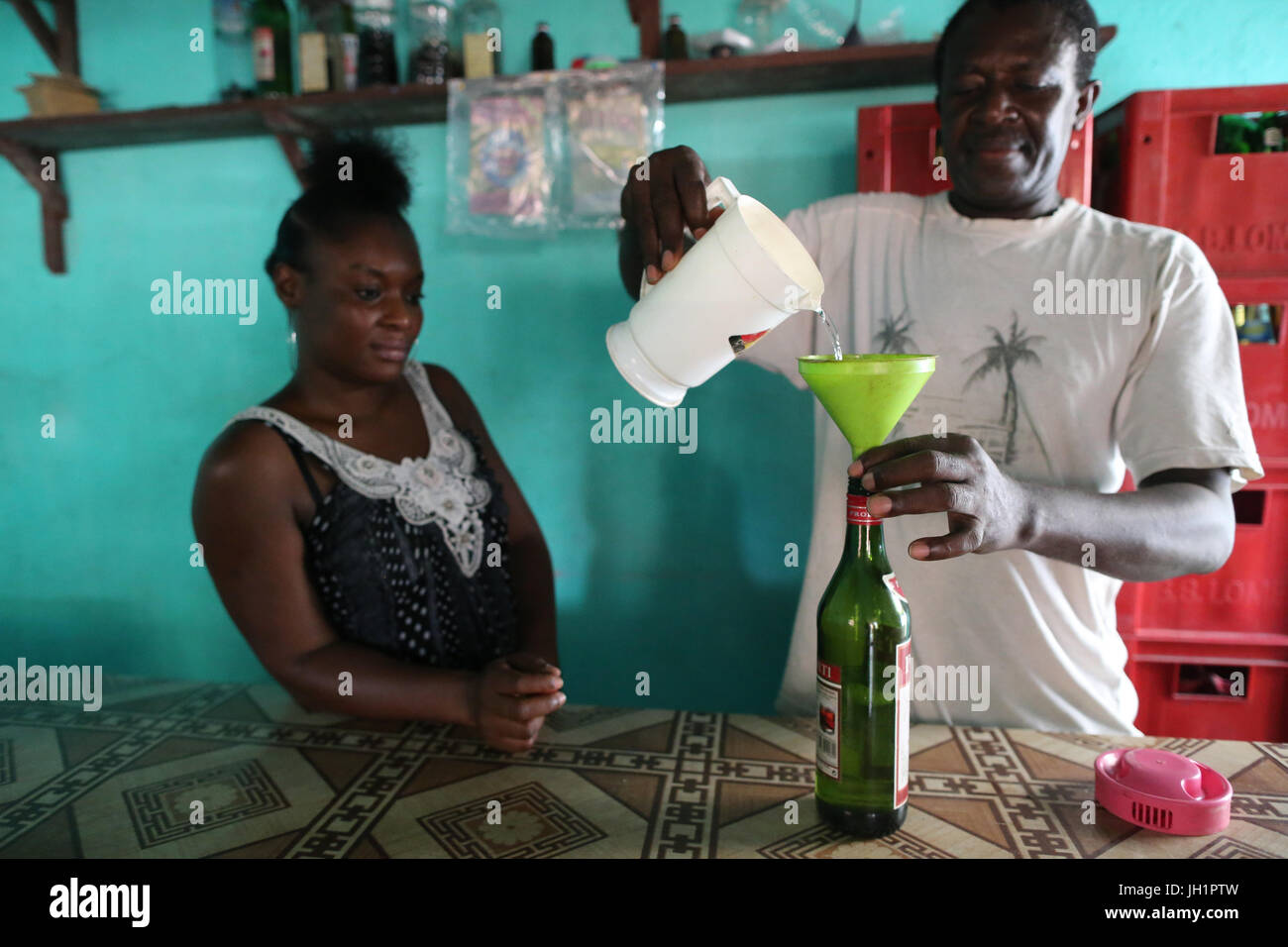 L'uomo versando palm alcool in una bottiglia. Lomé. Il Togo. Foto Stock