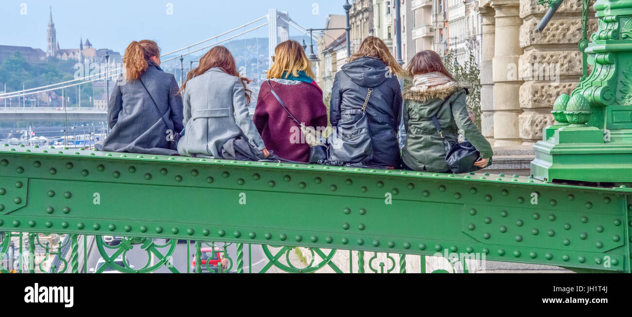Ragazza amici seduti sul ponte sopra il fiume Danubio a Budapest Foto Stock