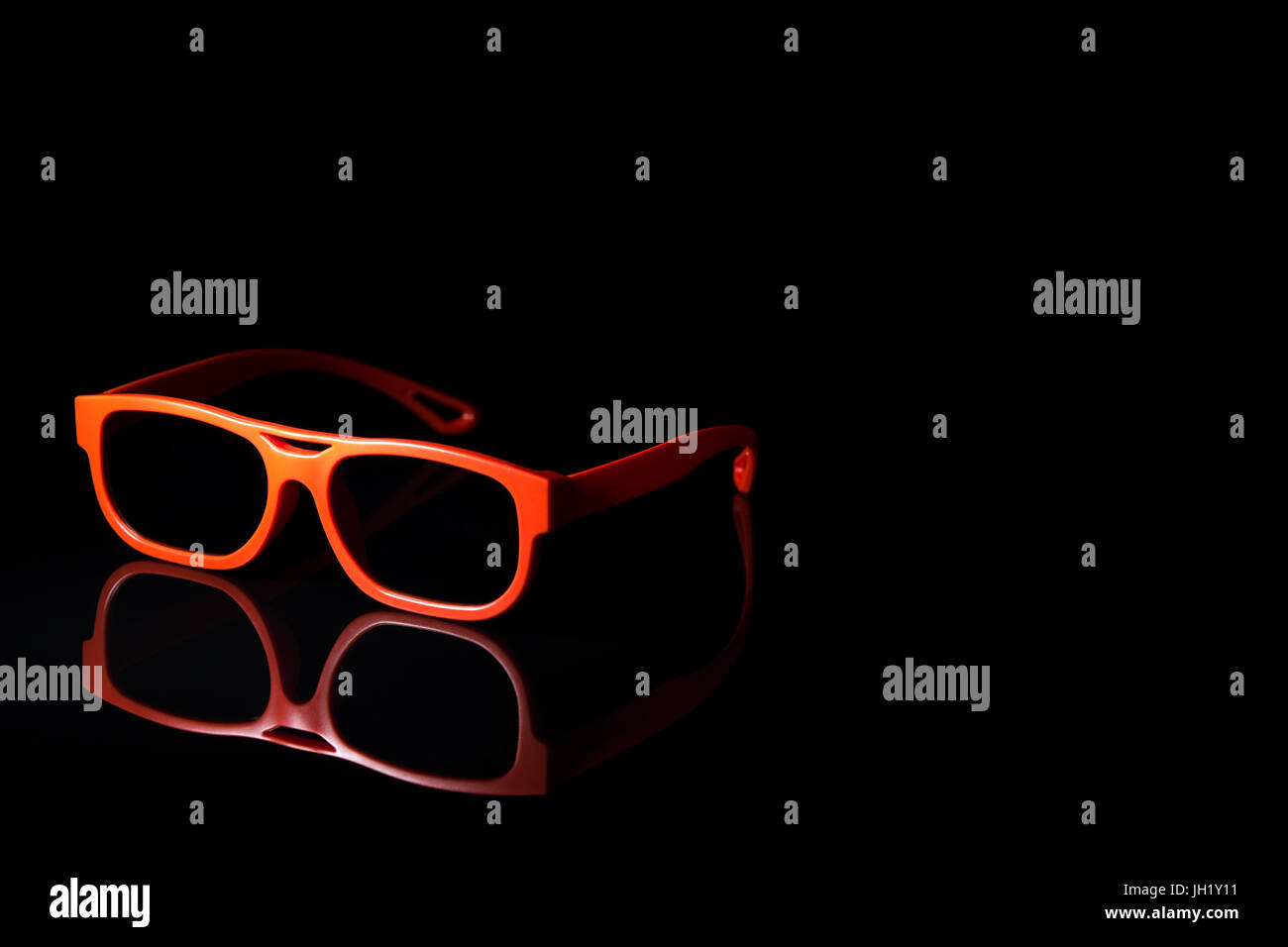 Orange occhiali 3d nero sulla superficie riflettente Foto Stock