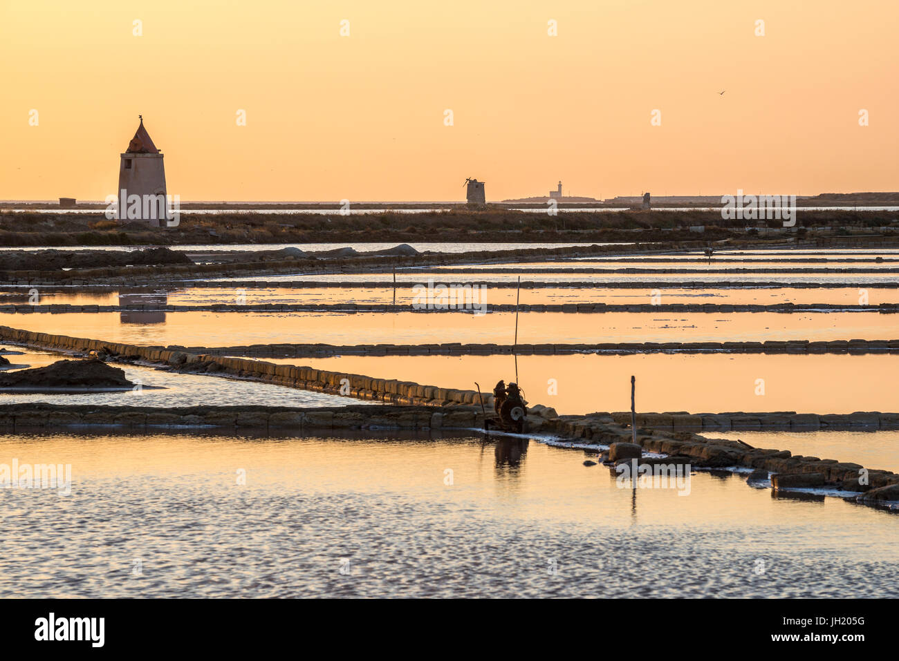 Tramonto tra le saline e mulini a vento presso la riserva naturale vicino a Nubia, a sud di Trapani, sulla costa occidentale della Sicilia, Italia. Foto Stock