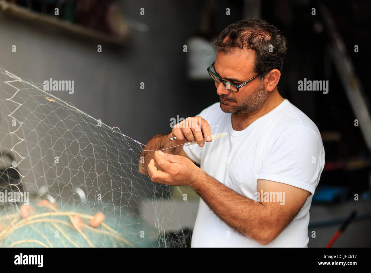 Marina Corricella, attentamente il pescatore mende reti da pesca, Isola di Procida e della baia di Napoli, Italia, Europa Foto Stock