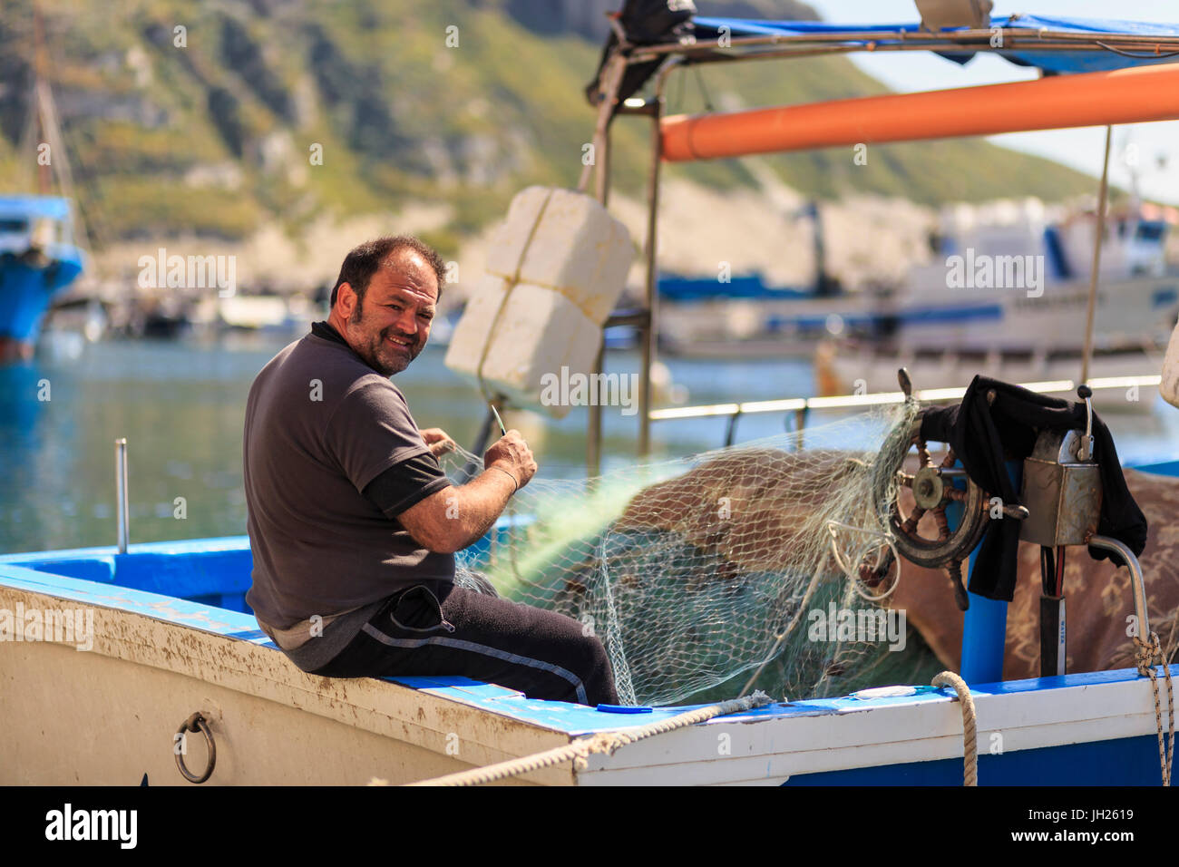 Marina Corricella Harbour, sorridente fisherman riassettavano le reti da pesca su una barca, Isola di Procida e della baia di Napoli, campania, Italy Foto Stock