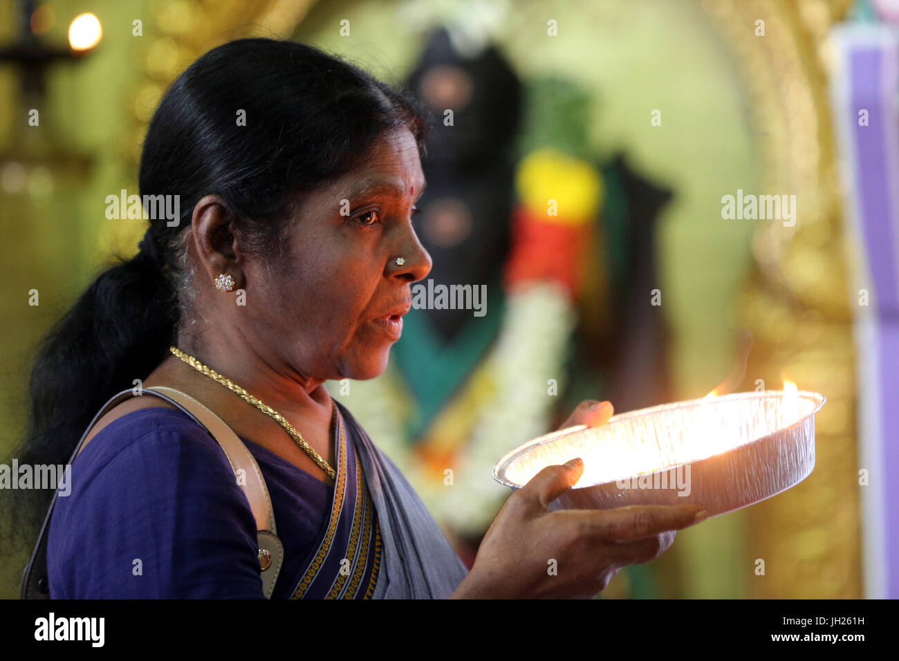 Sri Veeramakaliamman tempio indù. Donna indiana pregando. Offerta di olio. Singapore. Foto Stock