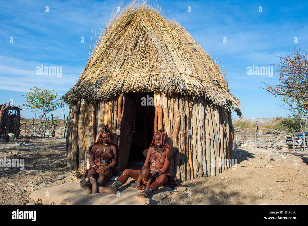 Le donne himba davanti alla loro capanna, Kaokoland, Namibia, Africa Foto Stock