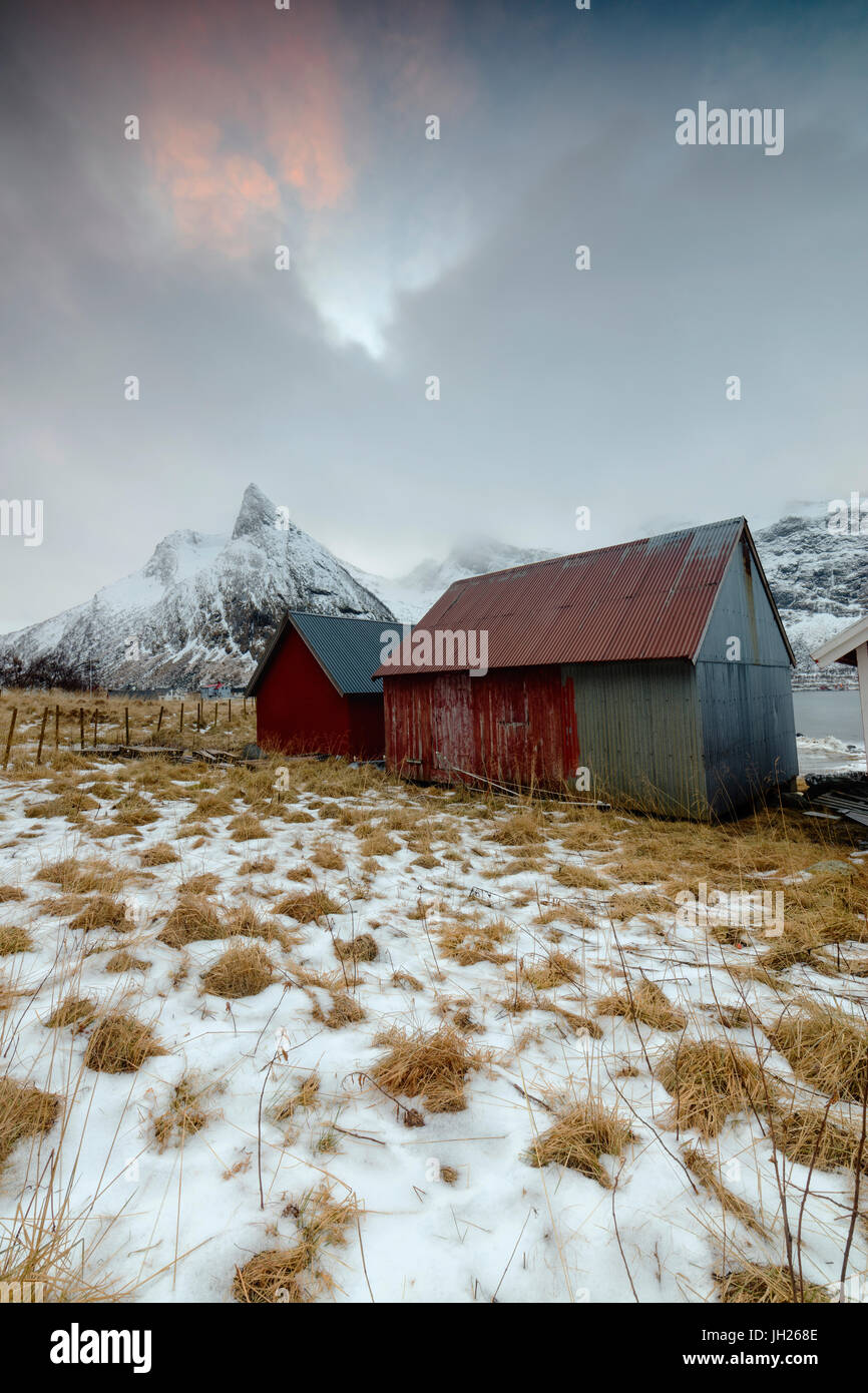 Nuvole sulle cime innevate sopra tipica capanna in legno chiamato Rorbu, Senja, Ersfjord, Troms County, Norvegia, Scandinavia, Europa Foto Stock