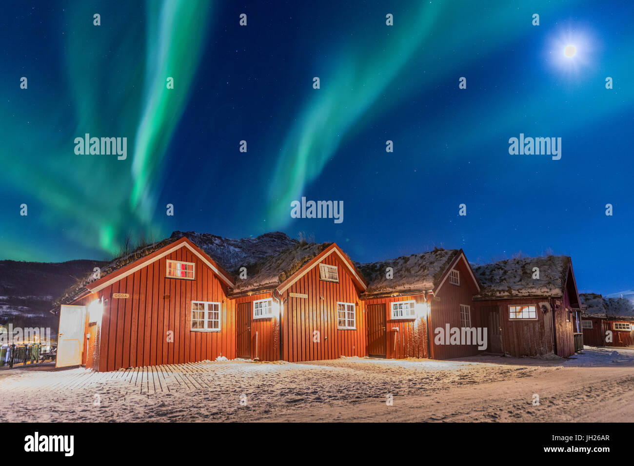 Le luci del nord e la luna illumina tipiche baite in legno chiamato Rorbu, Manndalen, Kafjord, Alpi Lyngen, Troms, Norvegia Foto Stock