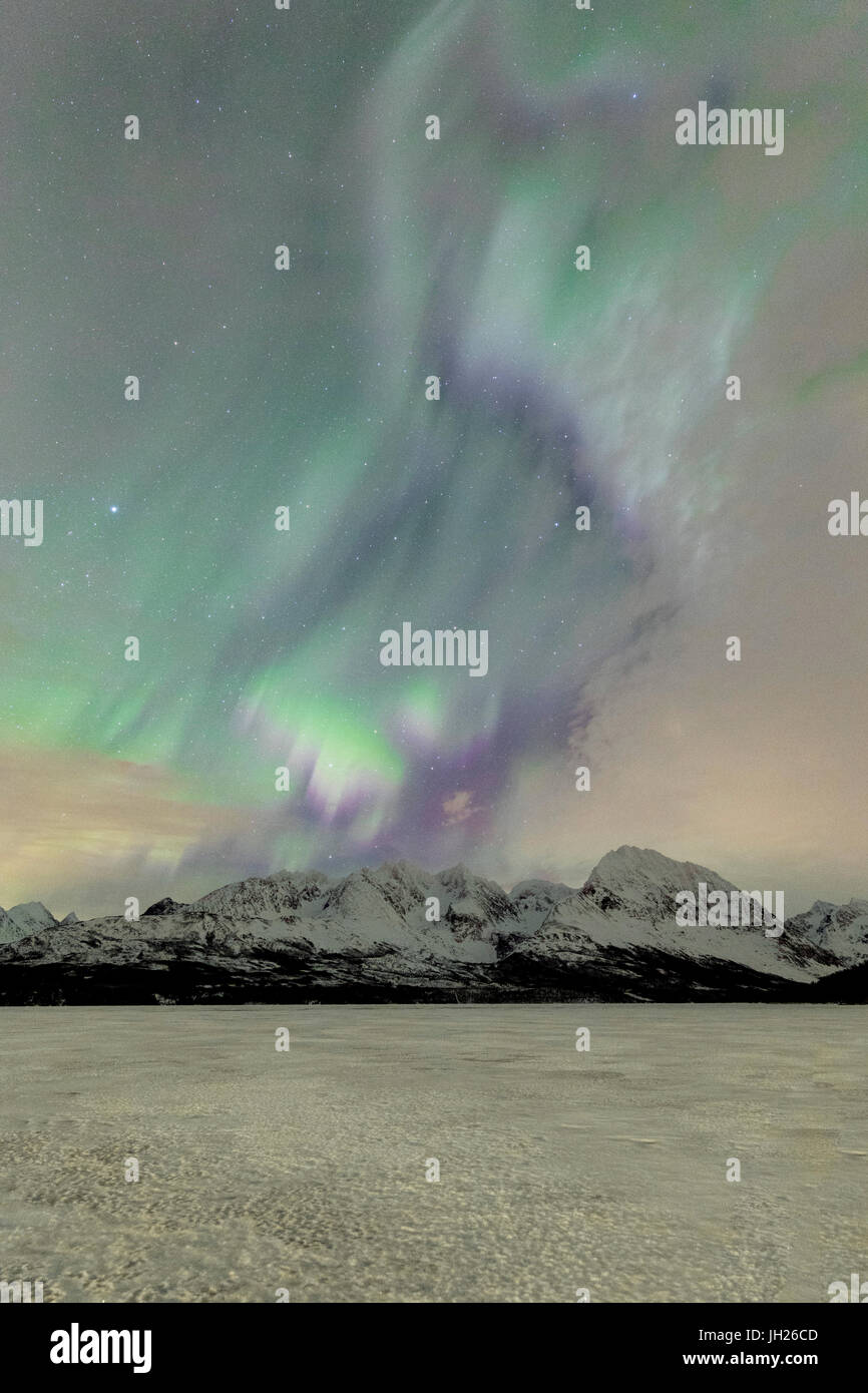 Il lago ghiacciato di Jaegervatnet incorniciato dalle luci del nord e il cielo stellato di notte polare, Alpi Lyngen, Troms, Norvegia Foto Stock