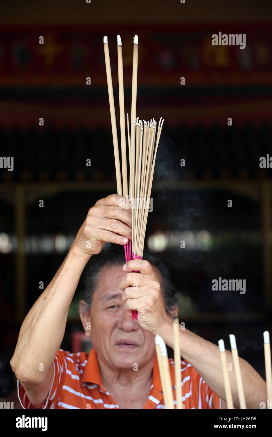 Lian Shan Shuang Lin monastero. Un uomo cinese di pregare e di offrire incenso. Adoratore buddista. La masterizzazione di bastoncini di incenso. Singapore. Foto Stock
