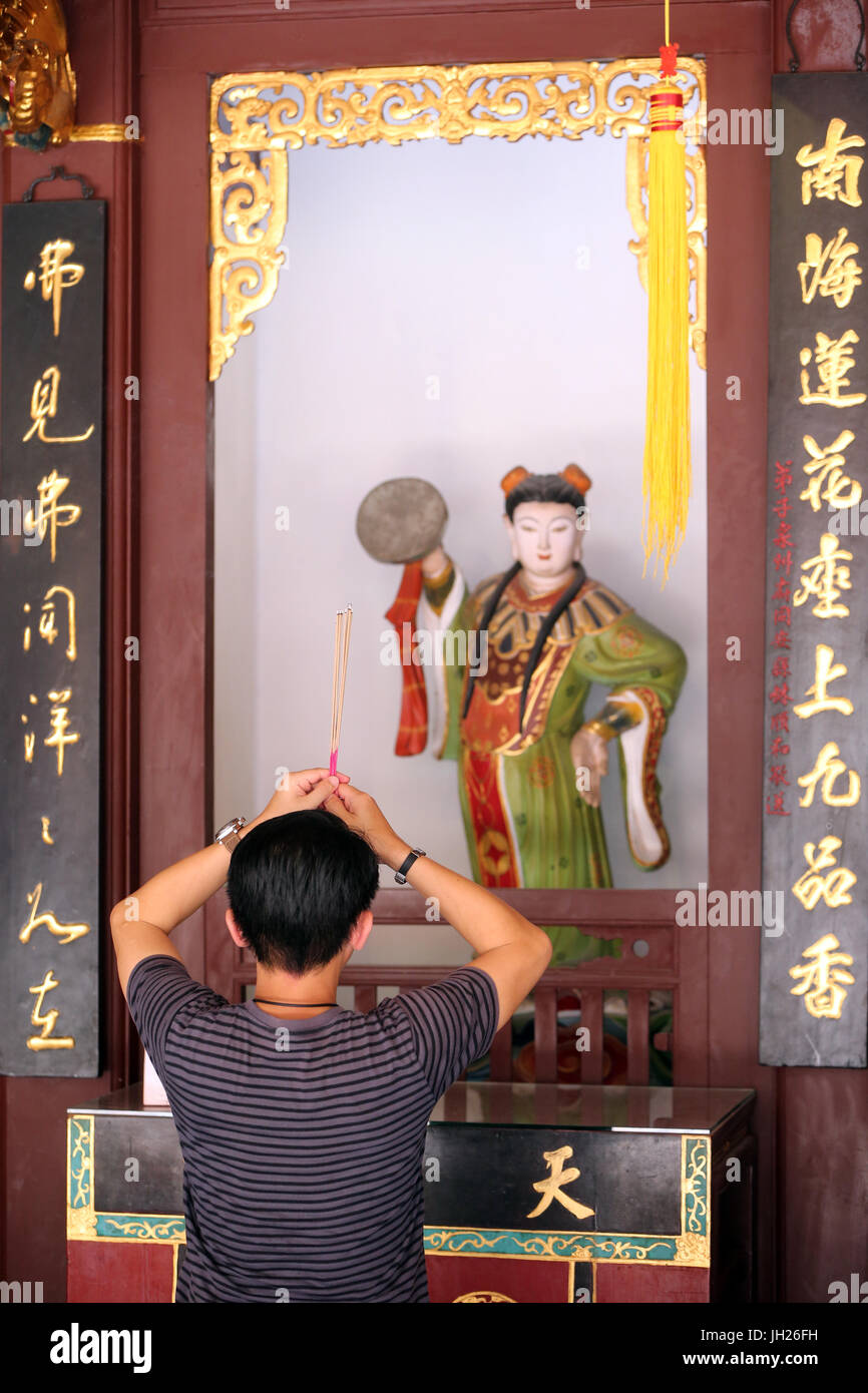 Thian Hock Keng Temple. Un giovane cinese di pregare e di offrire incenso. Adoratore buddista. La masterizzazione di bastoncini di incenso. Yue Gong Niang Niang : l m Foto Stock