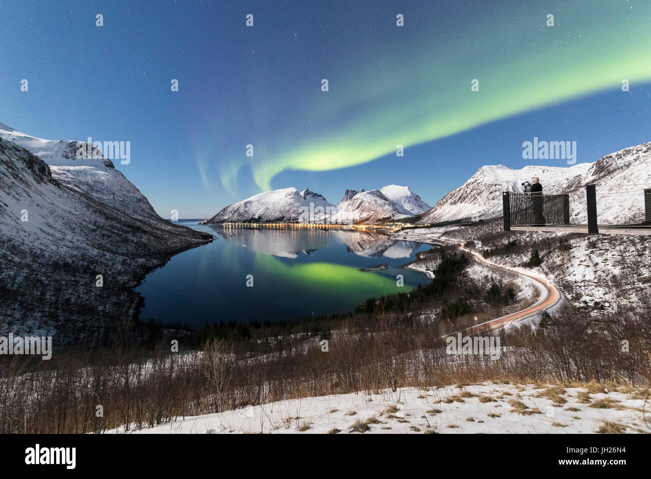 Fotografo sulla piattaforma ammira le luci del nord e stelle si riflette nel mare freddo, Bergsbotn, Senja, Troms, Norvegia Foto Stock