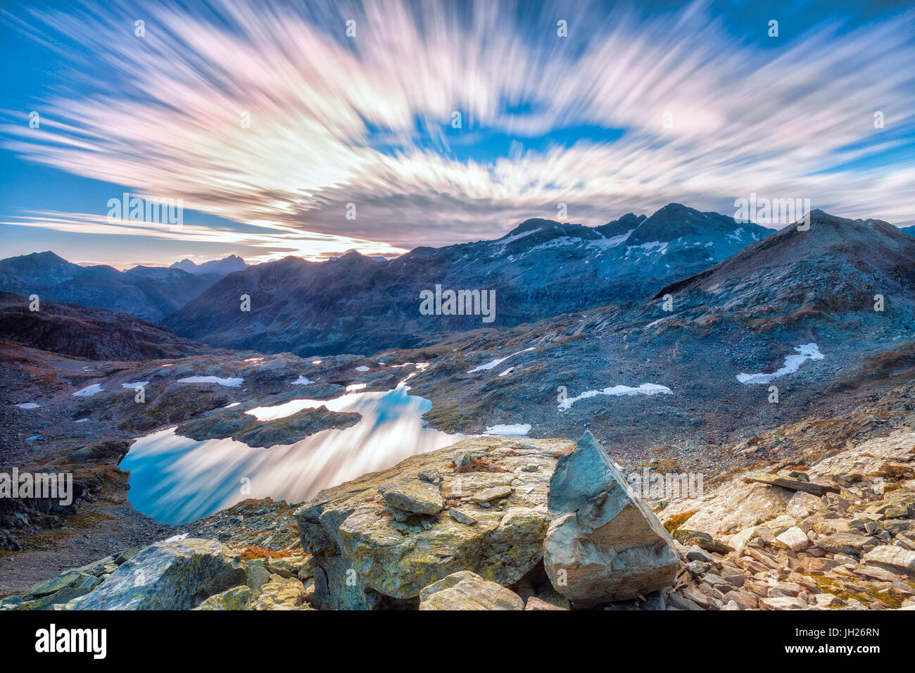 Nuvole all'alba sono riflesse in Lai Ghiacciato incorniciata da alte cime, Val Ursaregls, Val Chiavenna, Valtellina, Lombardia, Italia Foto Stock