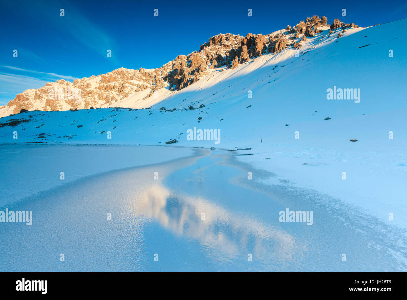 Vette innevate si riflette nel lago ghiacciato, Piz Umbrail all'alba, Valle del Braulio, Valtellina, Lombardia, Italia, Europa Foto Stock