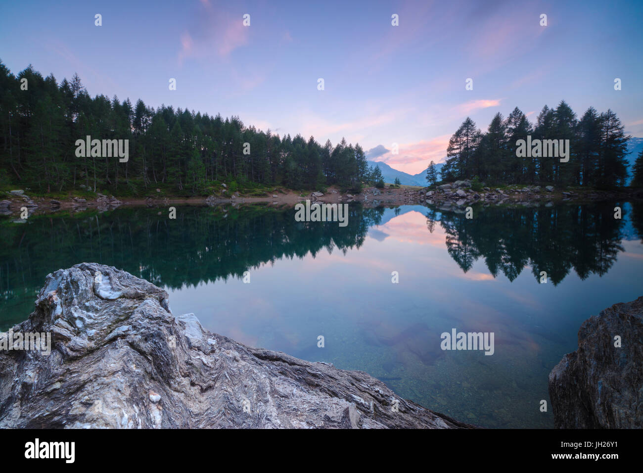 Gli alberi si riflette nel Lago Azzurro sotto il cielo rosa all'alba, Motta Madesimo, Valle Spluga, Sondrio, Valtellina, Lombardia, Italia Foto Stock
